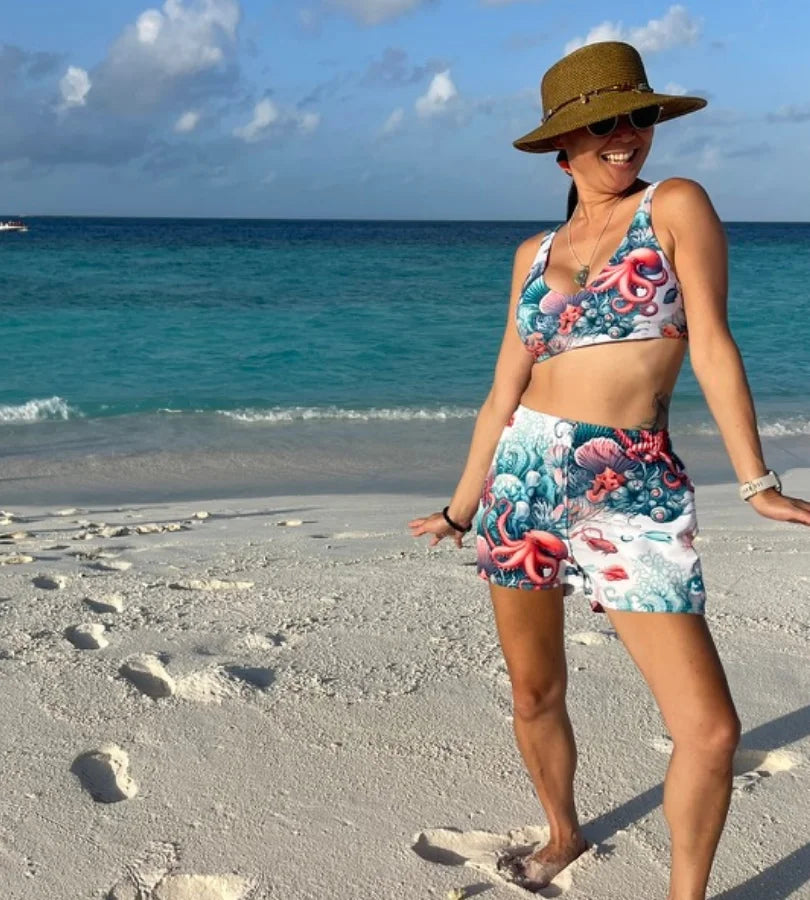 Women wear octopus shorts and octopus swimsuit on a Maldives beach. Perfect for snorkeling, diving, and exploring.