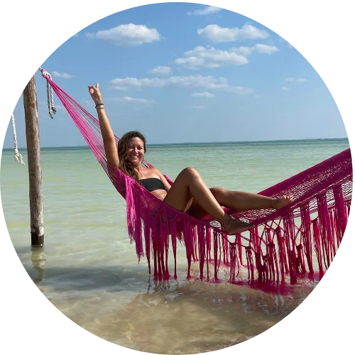 Woman relaxing in a pink hammock by the ocean