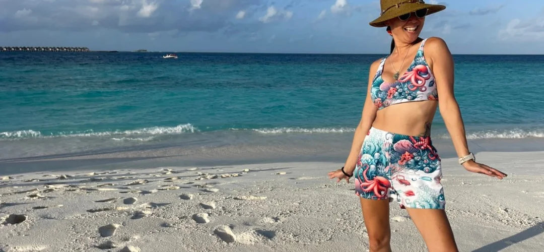 Octopus Reef Breezy Swim Shorts and Scuba Bikini Top. A woman is wearing octopus swimwear on a Maldives beach. Perfect for diving, snorkeling, and exploring. 