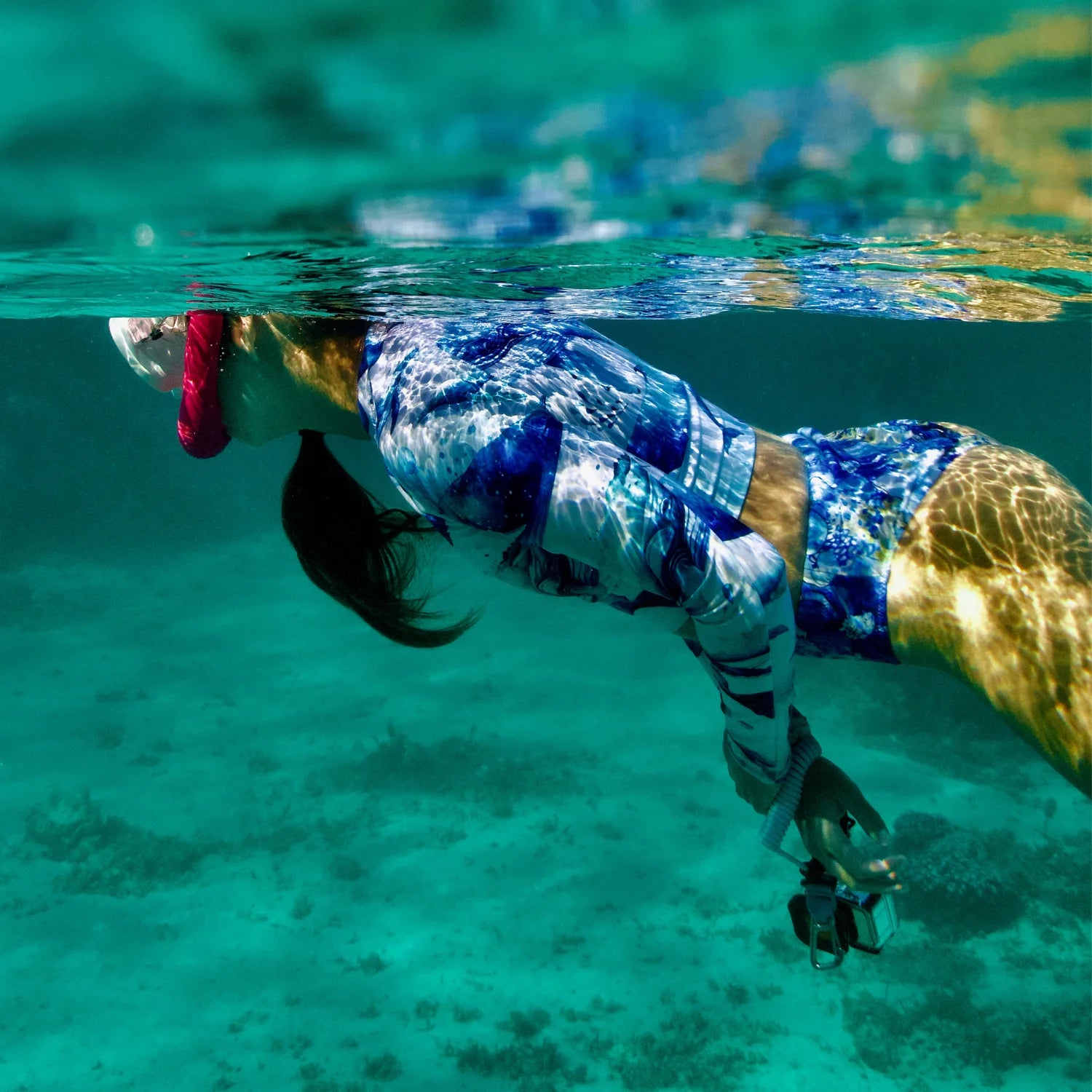 Person snorkeling underwater wearing sun protective rash guard and bikini for scuba divers in clear blue water