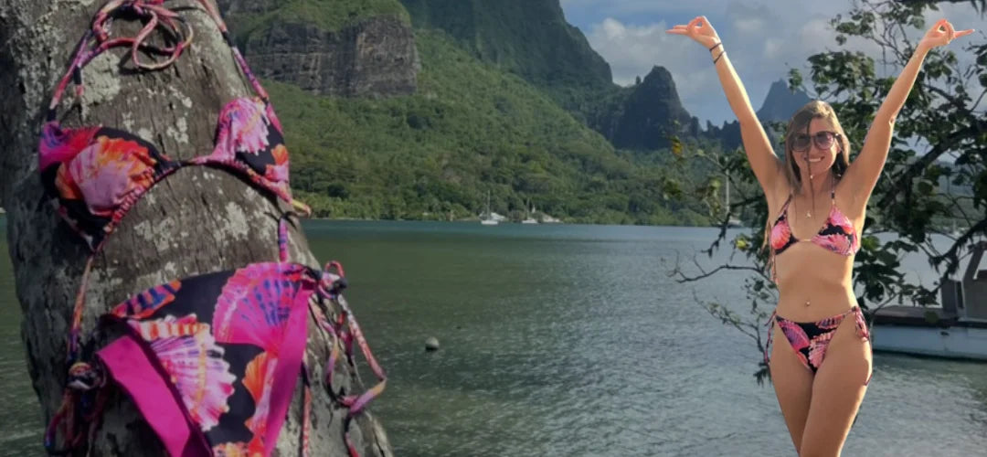 Woman in a colorful bikini standing by a body of water with mountains in the background. String bikinis for ocean lovers with ocean-inspired prints. 
